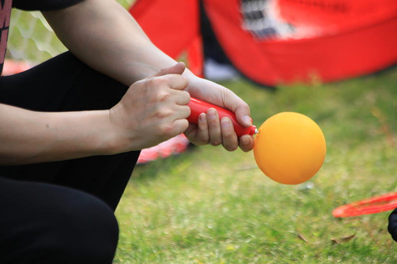 Bright orange balloon inflated by red pump for beach volleyball game