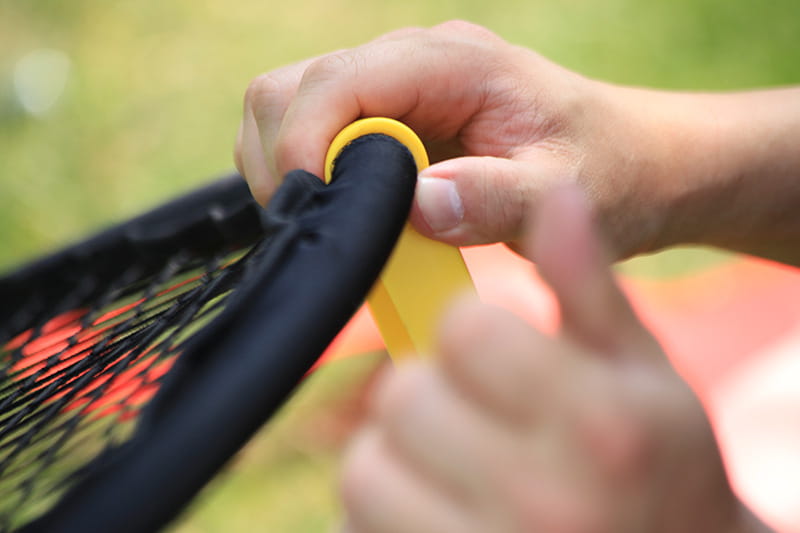 Yellow grip cap on black tennis racket handle for beach volleyball