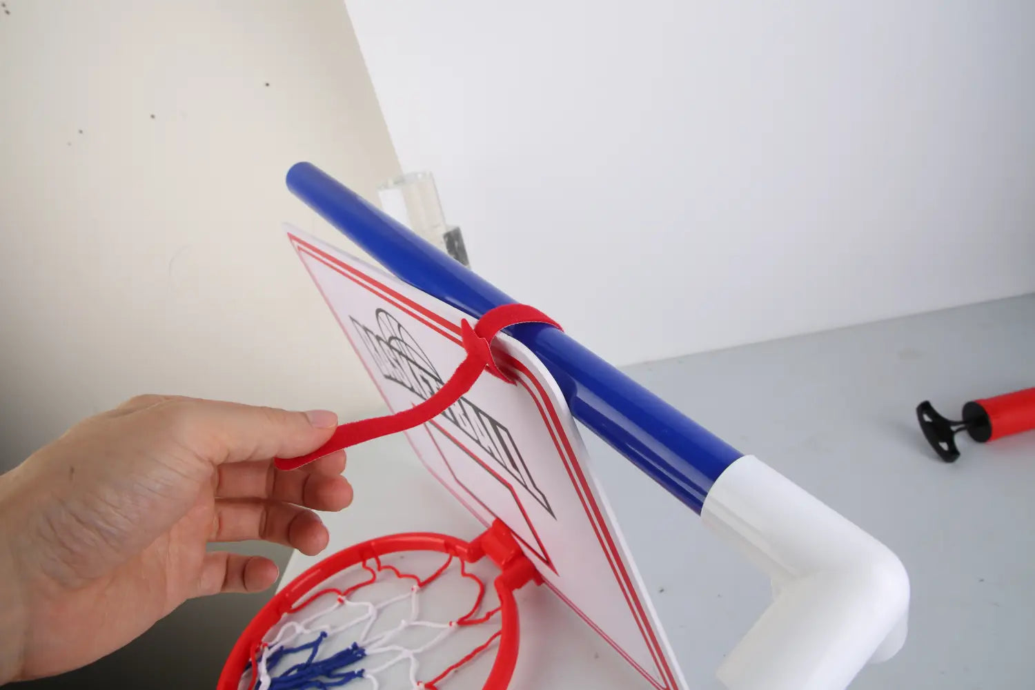 Back view of kids basketball game set hoop with hand on blue white backboard red net