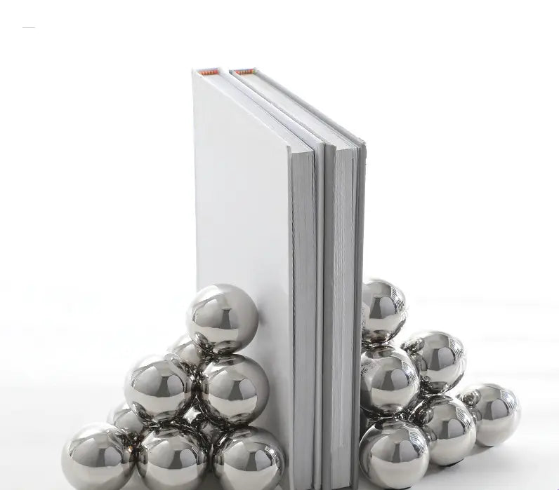 Shiny stainless steel ball bookends holding two white books