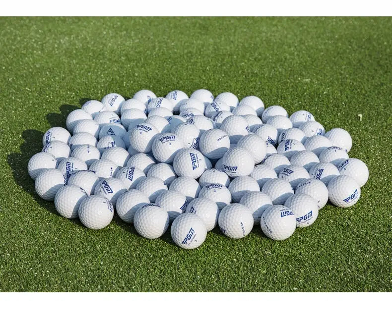Pile of white PGM golf balls with dimples on artificial turf