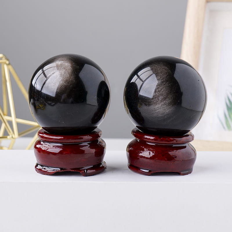 Two natural obsidian ball ornaments on glossy red bases